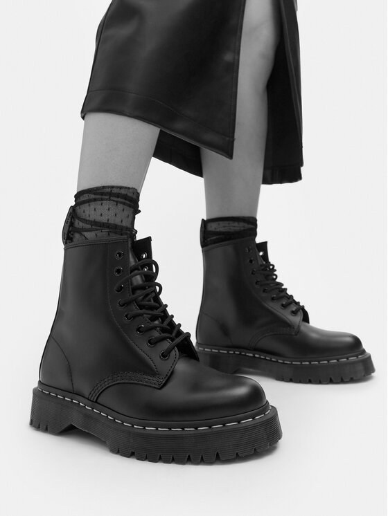 Czarne ośmiodziurkowe glany Dr. Martens 1460 z białym przeszyciem, noszone do skórzanej spódnicy