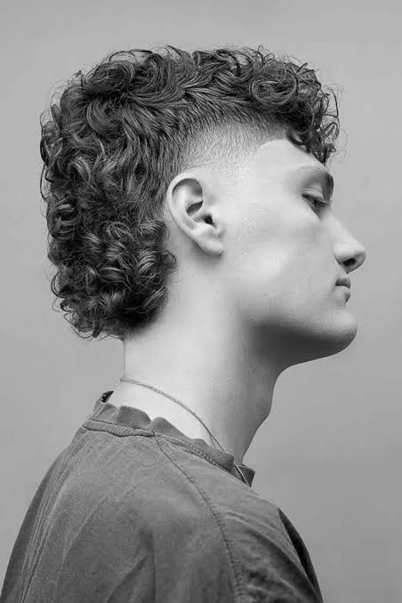 Fryzura mullet — krótko wygolone boki i góra przechodzące w dłuższe, kręcone włosy z tyłu głowy
